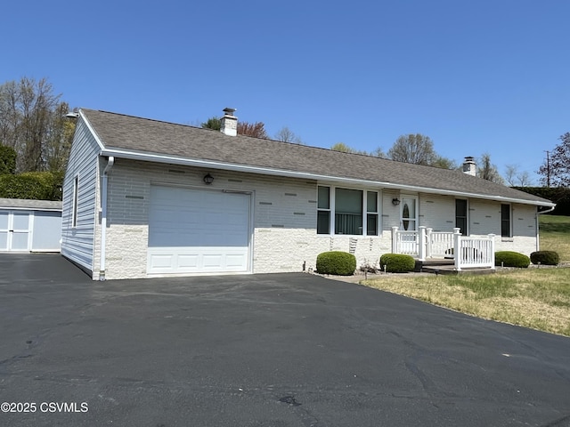 single story home with an attached garage, driveway, a chimney, and a porch