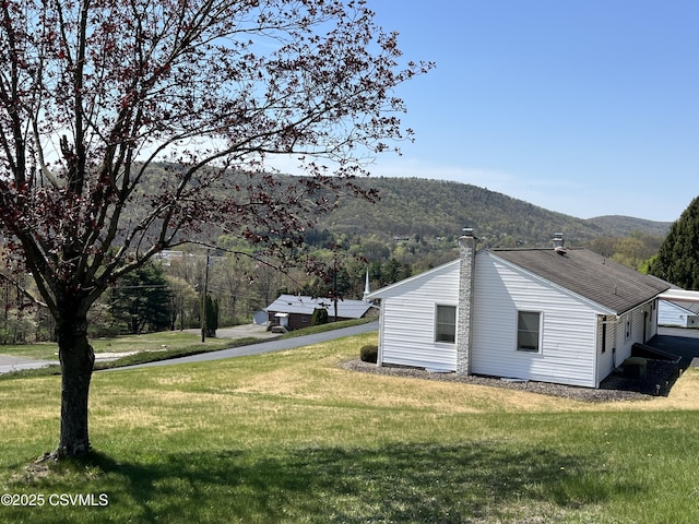 view of home's exterior featuring a chimney, a mountain view, and a yard