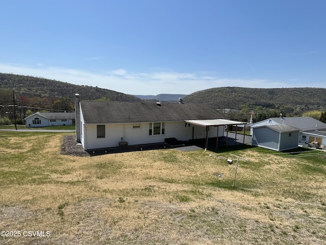 back of property with a lawn and a mountain view