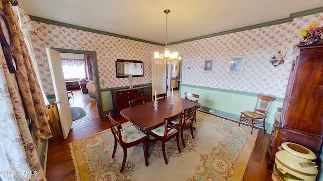 dining room with crown molding, wainscoting, hardwood / wood-style floors, a chandelier, and wallpapered walls