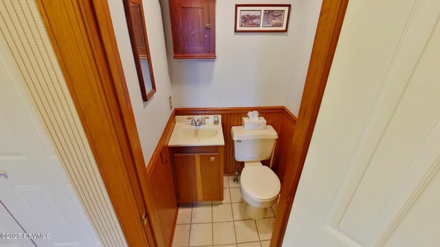 half bath featuring wainscoting, toilet, tile patterned flooring, and vanity