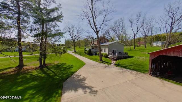 view of property's community with a lawn, a deck, and an outbuilding