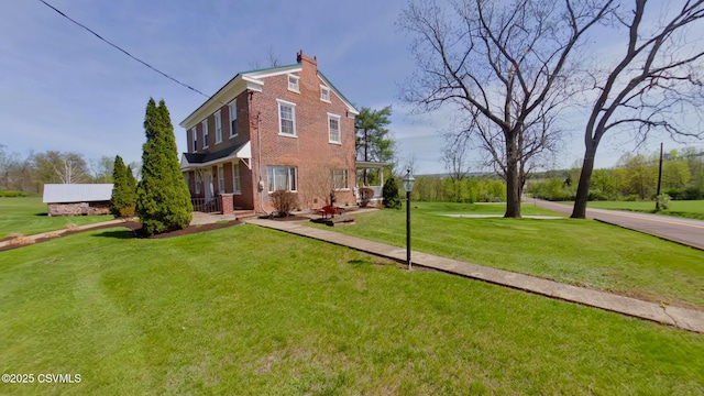 rear view of property featuring brick siding, a lawn, and a chimney
