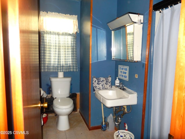 bathroom with baseboards, toilet, tile patterned flooring, and a sink