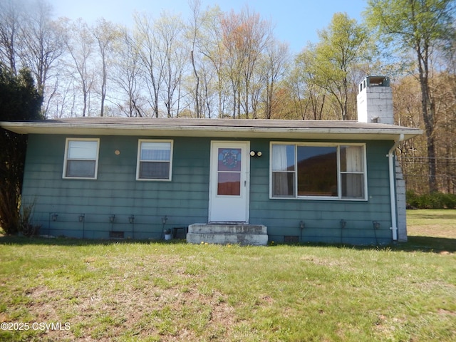 view of front of house with a front yard, crawl space, and a chimney