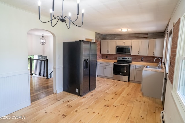 302 Walnut St, Selinsgrove, PA 17870 - kitchen featuring arched walkways, stainless steel appliances, light countertops, a sink, and a notable chandelier