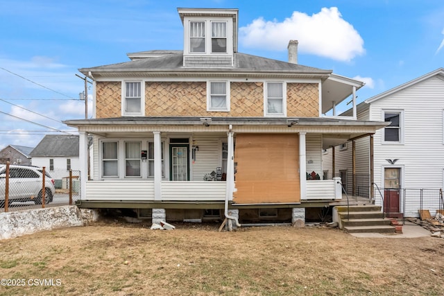 view of front facade with covered porch, fence, and a front yard