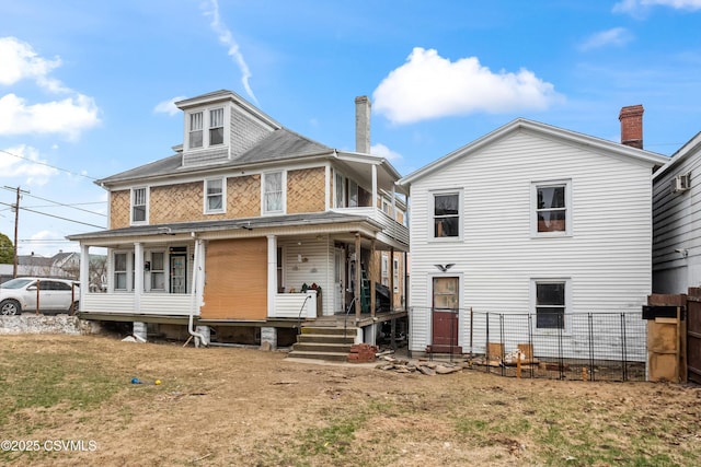 rear view of house with fence, a porch, and a yard