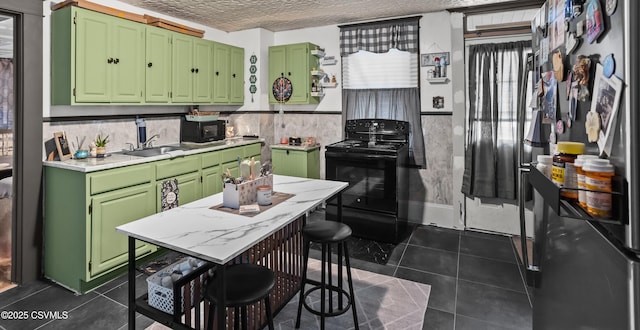 kitchen featuring a sink, green cabinets, light countertops, black appliances, and dark tile patterned floors