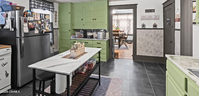 kitchen with green cabinets, dark tile patterned floors, and freestanding refrigerator