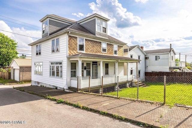traditional style home featuring a front yard, a porch, an outbuilding, and a fenced front yard
