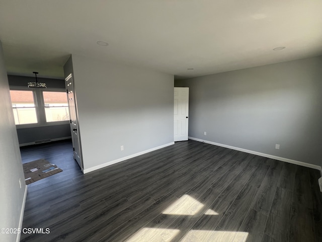 spare room with baseboards, dark wood-style flooring, a notable chandelier, and visible vents