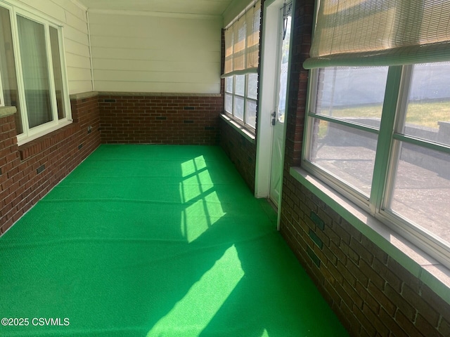 unfurnished sunroom with brick wall