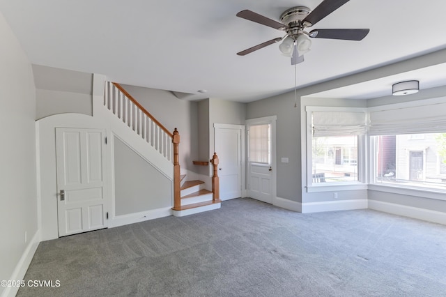 interior space featuring baseboards, a ceiling fan, and stairway