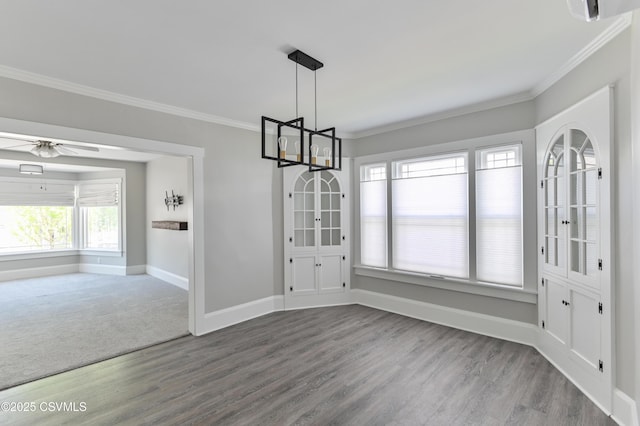 unfurnished dining area with crown molding, baseboards, wood finished floors, and ceiling fan with notable chandelier