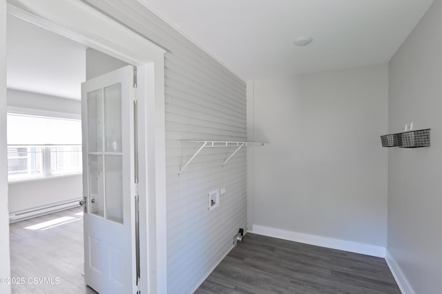 laundry area with baseboards, a baseboard radiator, and wood finished floors