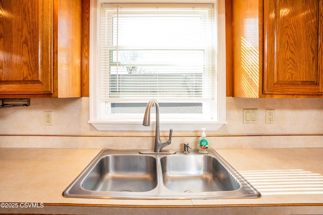 kitchen featuring a sink, light countertops, brown cabinets, and a wealth of natural light