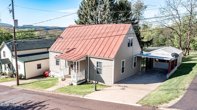 view of front facade featuring a front yard, a standing seam roof, a carport, driveway, and metal roof