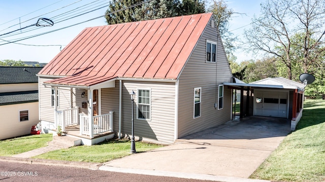 view of front of home with driveway, a standing seam roof, metal roof, a front yard, and an outbuilding