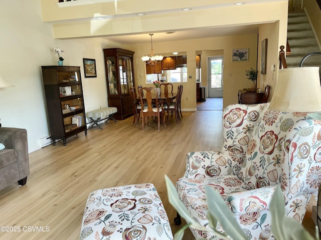 living room featuring a chandelier, stairs, baseboards, light wood-type flooring, and a baseboard radiator