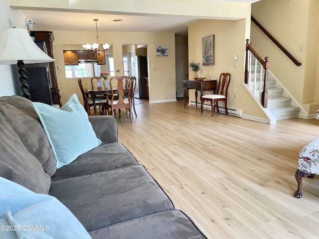 living area with baseboards, stairway, light wood-type flooring, a chandelier, and a baseboard radiator