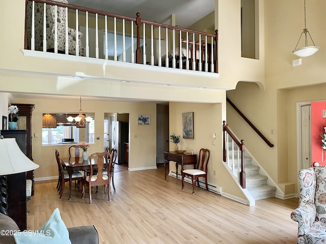 living area with wood finished floors, a high ceiling, and baseboard heating