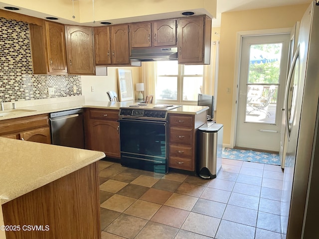 kitchen featuring light countertops, decorative backsplash, under cabinet range hood, and stainless steel appliances