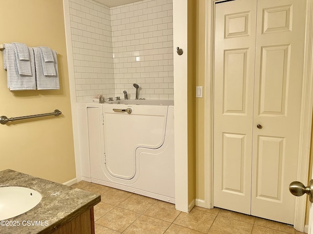 bathroom with tile patterned flooring, vanity, baseboards, washer / dryer, and a closet