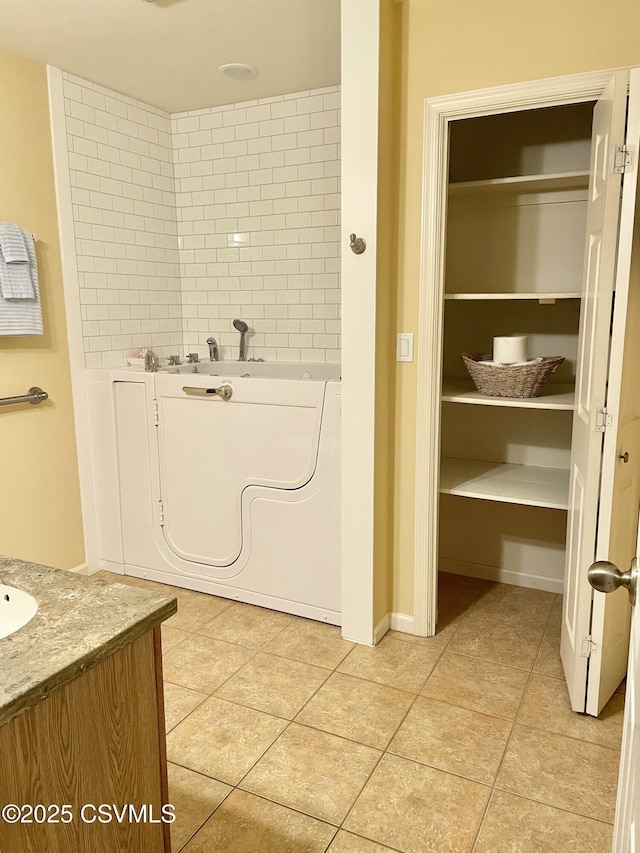 full bath featuring tile patterned flooring, a bathing tub, and vanity