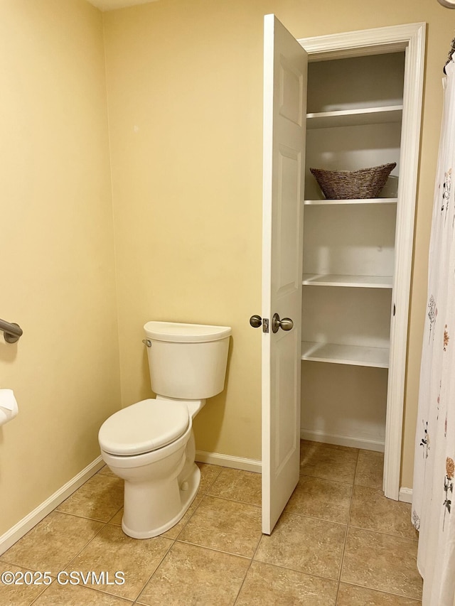 bathroom featuring baseboards, tile patterned flooring, and toilet