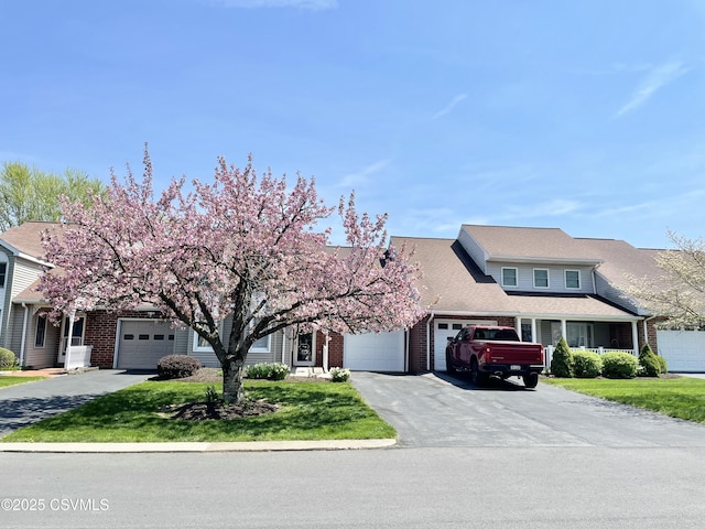 view of front facade featuring a garage, a front yard, brick siding, and aphalt driveway