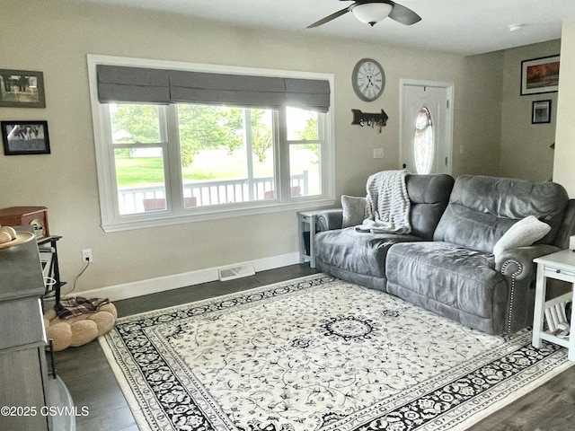 living area with dark wood-style flooring, ceiling fan, visible vents, and baseboards