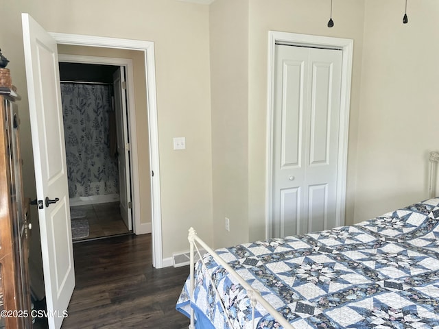 bedroom with dark wood-style flooring, baseboards, and a closet