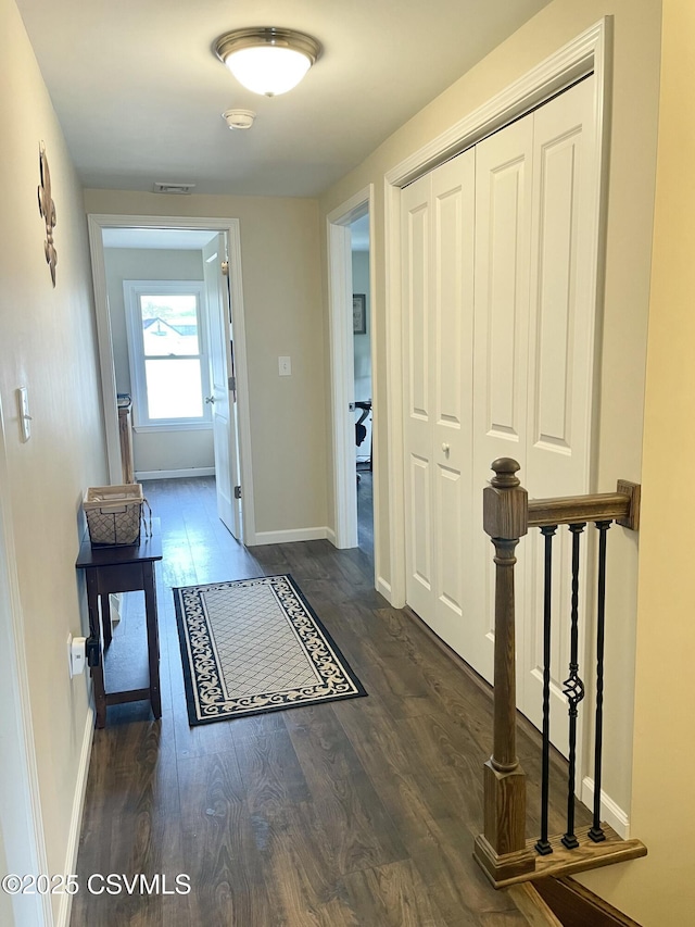 interior space with baseboards, visible vents, wood finished floors, and an upstairs landing