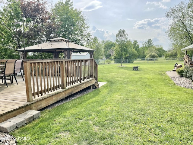 view of yard with a gazebo, a fire pit, a wooden deck, and a fenced backyard