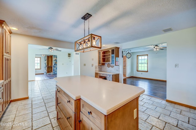 kitchen with open floor plan, ceiling fan, baseboards, plenty of natural light, and a textured ceiling