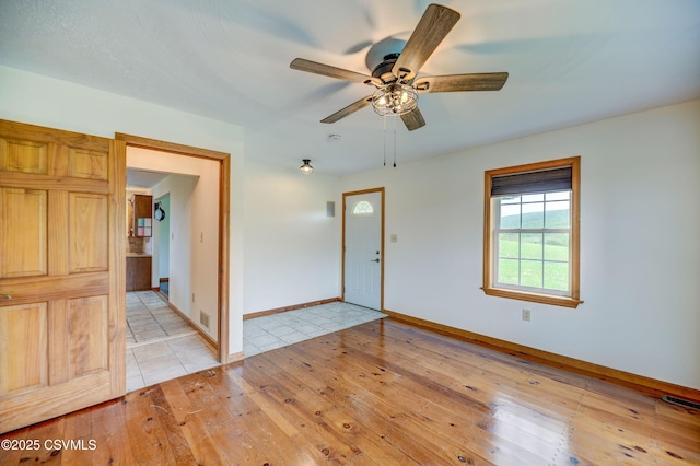entrance foyer with a ceiling fan, baseboards, and light wood-type flooring
