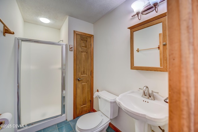 full bath with a sink, a textured ceiling, a stall shower, toilet, and tile patterned floors