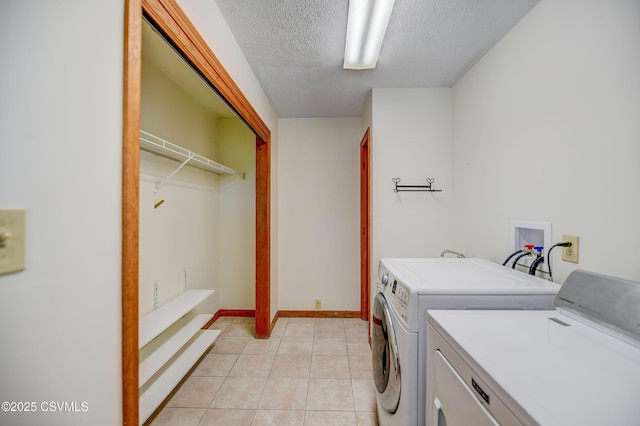 laundry room with separate washer and dryer, a textured ceiling, light tile patterned floors, and baseboards
