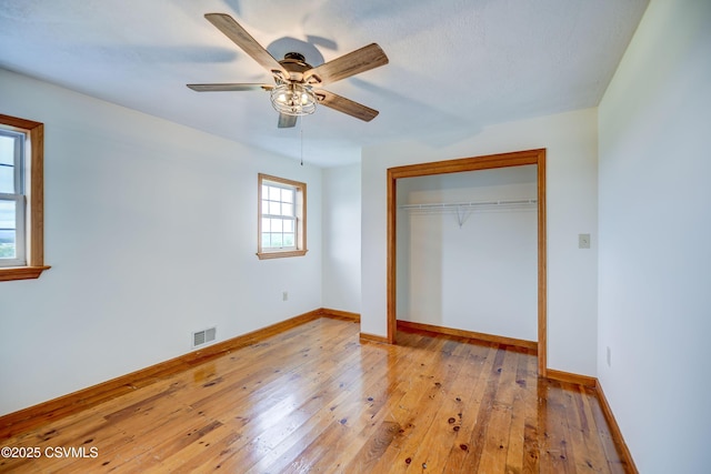 unfurnished bedroom featuring a closet, light wood-style flooring, baseboards, and a ceiling fan