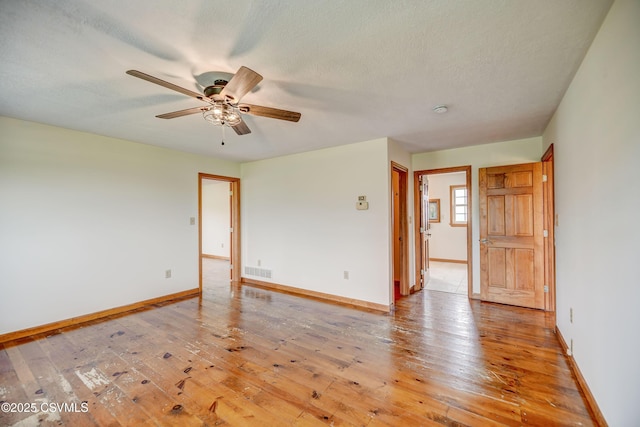 unfurnished room featuring a ceiling fan, baseboards, light wood-type flooring, and a textured ceiling