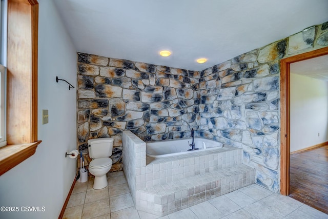bathroom featuring toilet, a garden tub, tile patterned floors, and baseboards