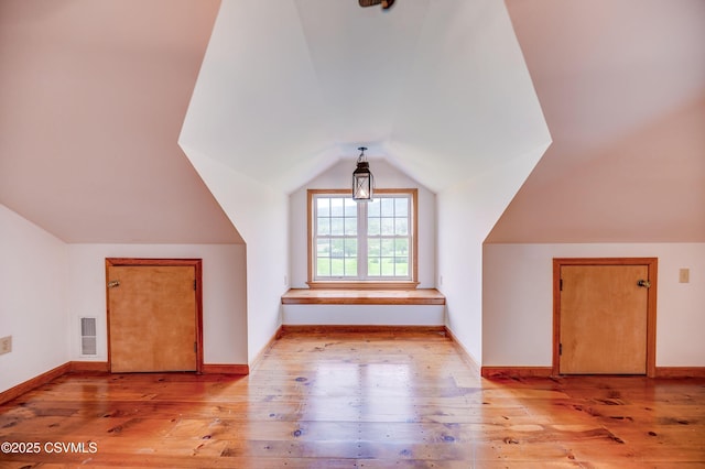 bonus room featuring lofted ceiling, light wood-type flooring, and baseboards