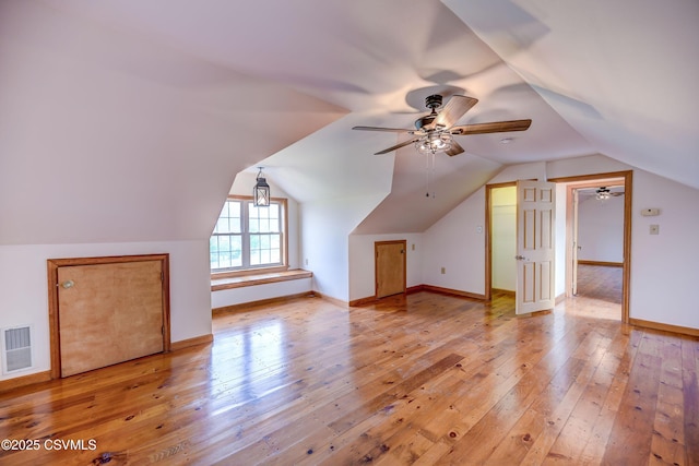 additional living space with hardwood / wood-style flooring, a ceiling fan, vaulted ceiling, and baseboards