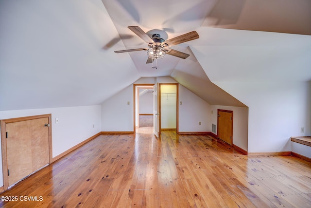 additional living space featuring light wood-style flooring, vaulted ceiling, a ceiling fan, and baseboards