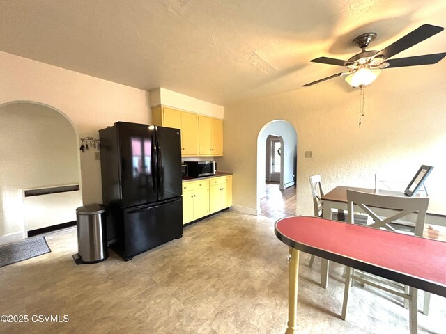 735 E 3rd St, Bloomsburg, PA 17815 - kitchen with arched walkways, freestanding refrigerator, stainless steel microwave, ceiling fan, and cream cabinets