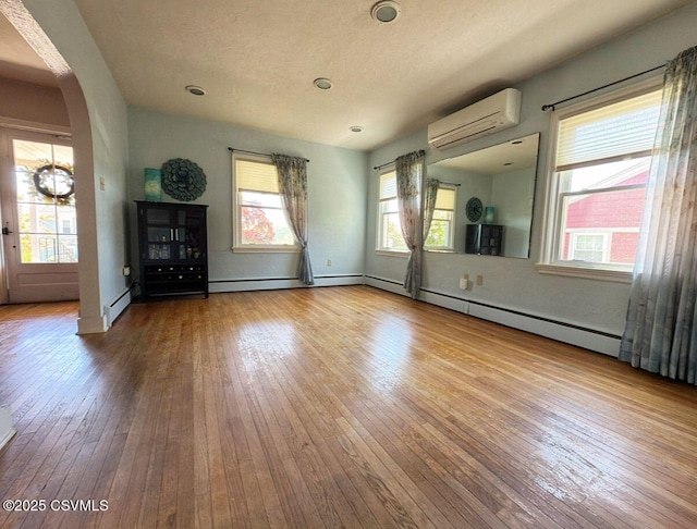 735 E 3rd St, Bloomsburg, PA 17815 - spare room with a wall mounted air conditioner, arched walkways, hardwood / wood-style floors, and healthy amount of natural light