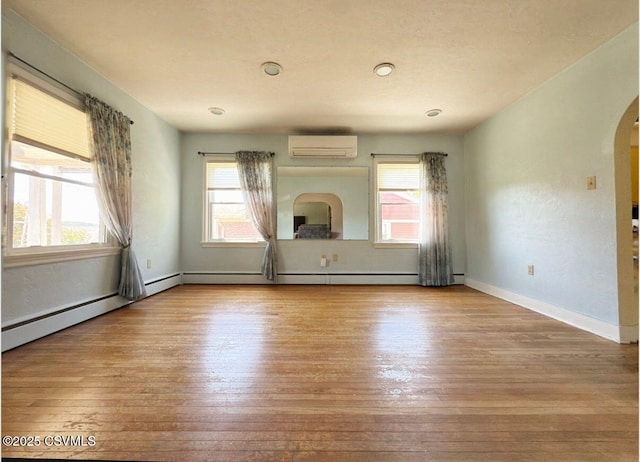 735 E 3rd St, Bloomsburg, PA 17815 - unfurnished living room with wood-type flooring, arched walkways, a wall mounted AC, and baseboard heating