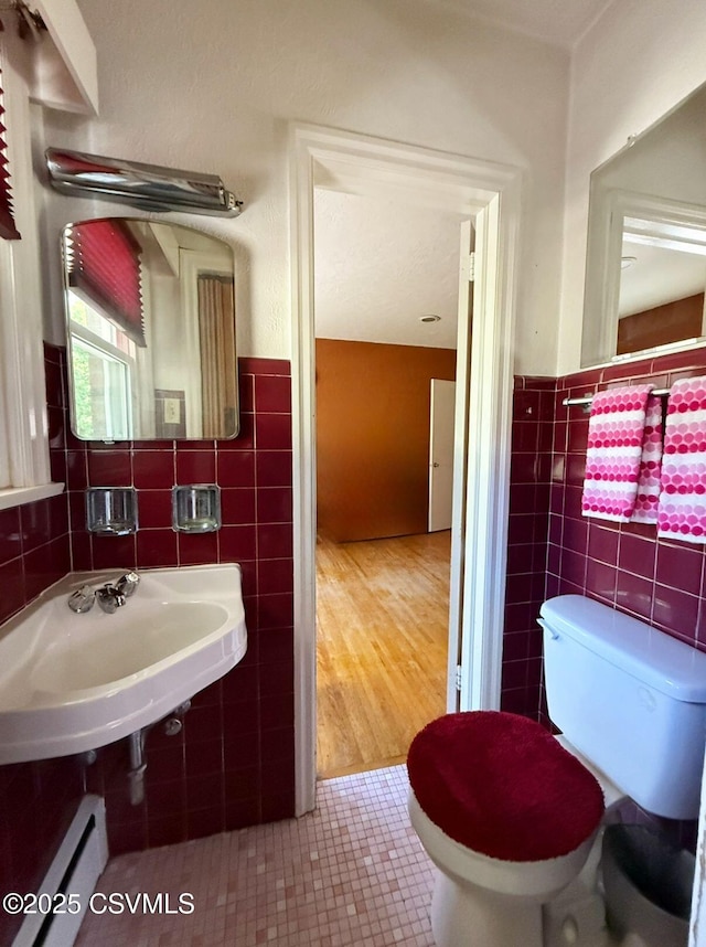 735 E 3rd St, Bloomsburg, PA 17815 - bathroom with tile walls, a baseboard radiator, tile patterned floors, toilet, and a wainscoted wall