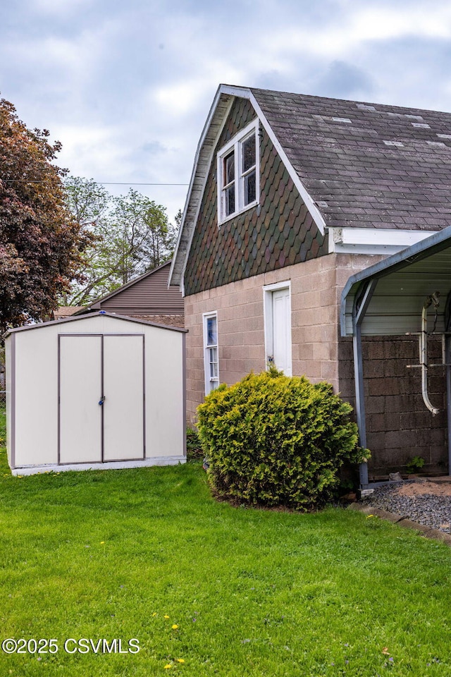 341 Dewart St, Danville, PA 17821 - view of property exterior featuring concrete block siding, a shed, a lawn, an outdoor structure, and roof with shingles